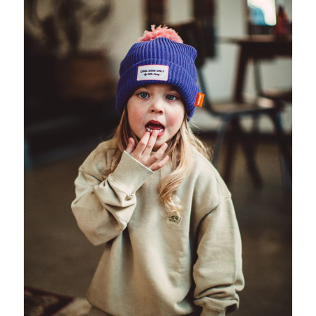 Petite fille avec bonnet violet et pompom rose de Hello Hossy