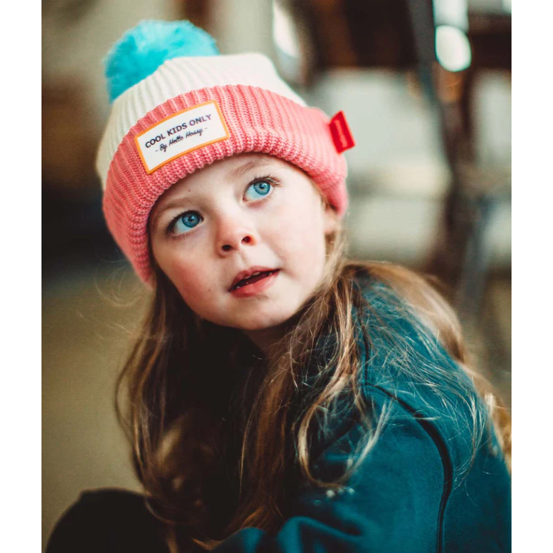 petite fille avec bonnet rose et blanc avec super pompom bleu